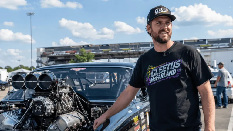 Cleetus McFarland net worth subject standing beside his race car